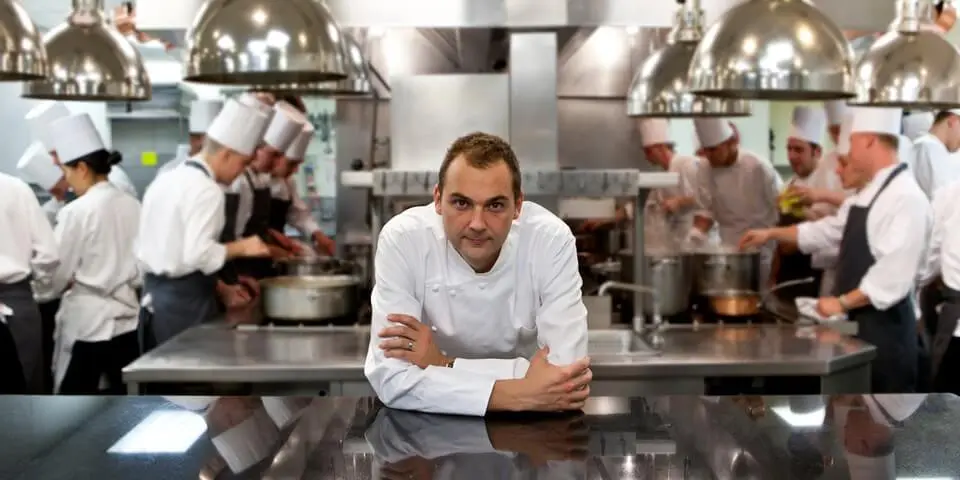 chef leaning on the metal kitchen table