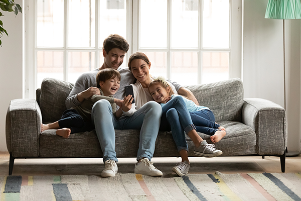 family of four laughing while hugging on the couch